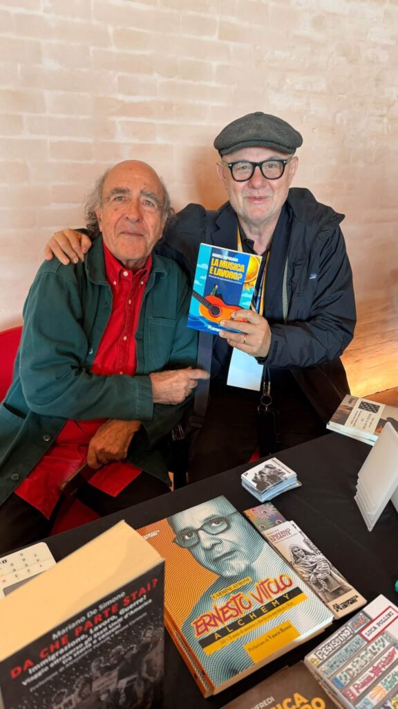 Renato Marengo e Giordano Sangiorgi tengono in mano il libro La musica è lavoro? al Salone del Disco di Faenza, MEI 2026.